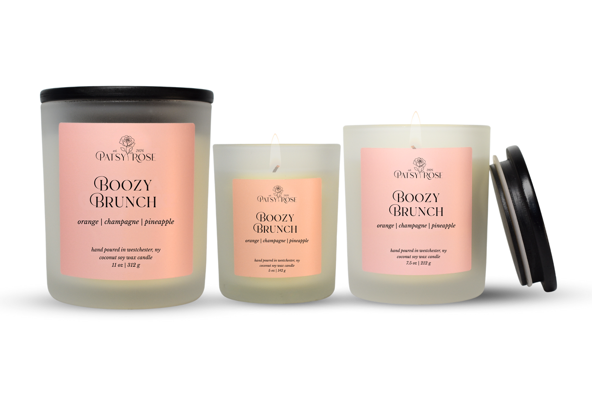 Three hand-poured coconut soy wax candles by Patsy Rose in the Boozy Brunch scent, shown in different glass sizes with a black lid on the largest jar and one smaller jar beside it, on a white background.
