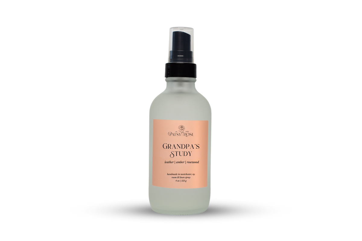 A 4 oz room and linen spray made by Patsy Rose in a frosted glass bottle with a peach label that says "Grandpa's Study" with a scent of "leather, amber, rosewood" on a white background