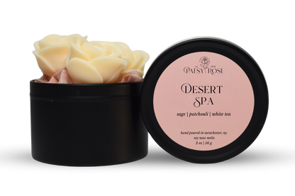 Hand-poured, rose shaped soy wax melts made by Patsy Rose with black tins and a peach label that says "Desert Spa" with scent notes of "sage, patchouli, white tea".