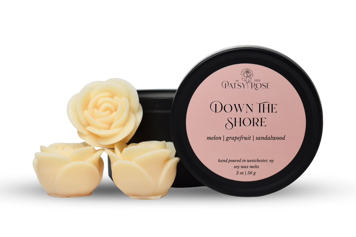 Hand-poured, rose shaped soy wax melts made by Patsy Rose with black tins and a peach label that says "Down The Shore" with scent notes of "melon, grapefruit, sandalwood".