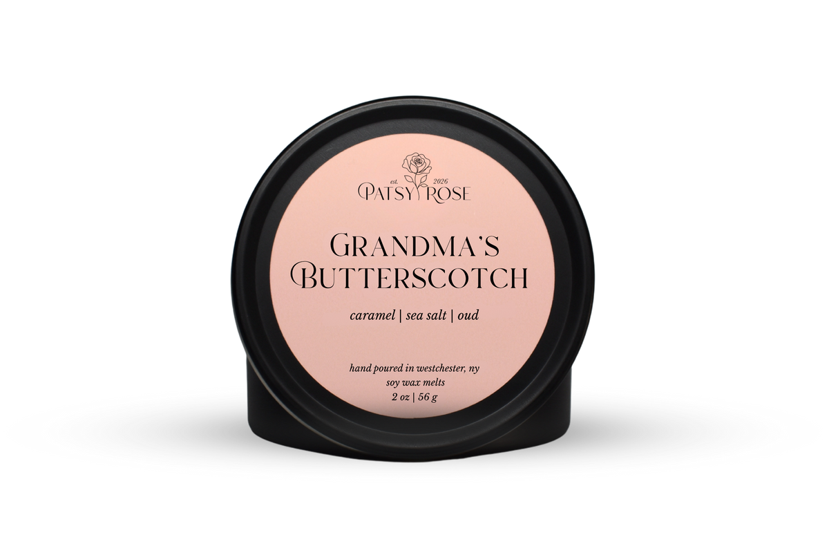 Hand-poured soy wax melts made by Patsy Rose with black tins and a peach label that says "Grandma's Butterscotch" with scent notes of "caramel, sea salt, oud".