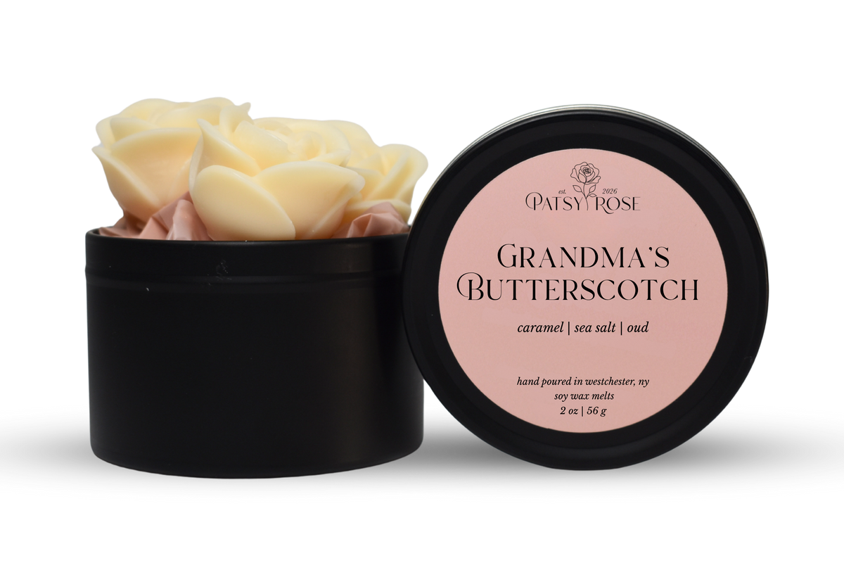Hand-poured, rose shaped soy wax melts made by Patsy Rose with black tins and a peach label that says "Grandma's Butterscotch" with scent notes of "caramel, sea salt, oud".