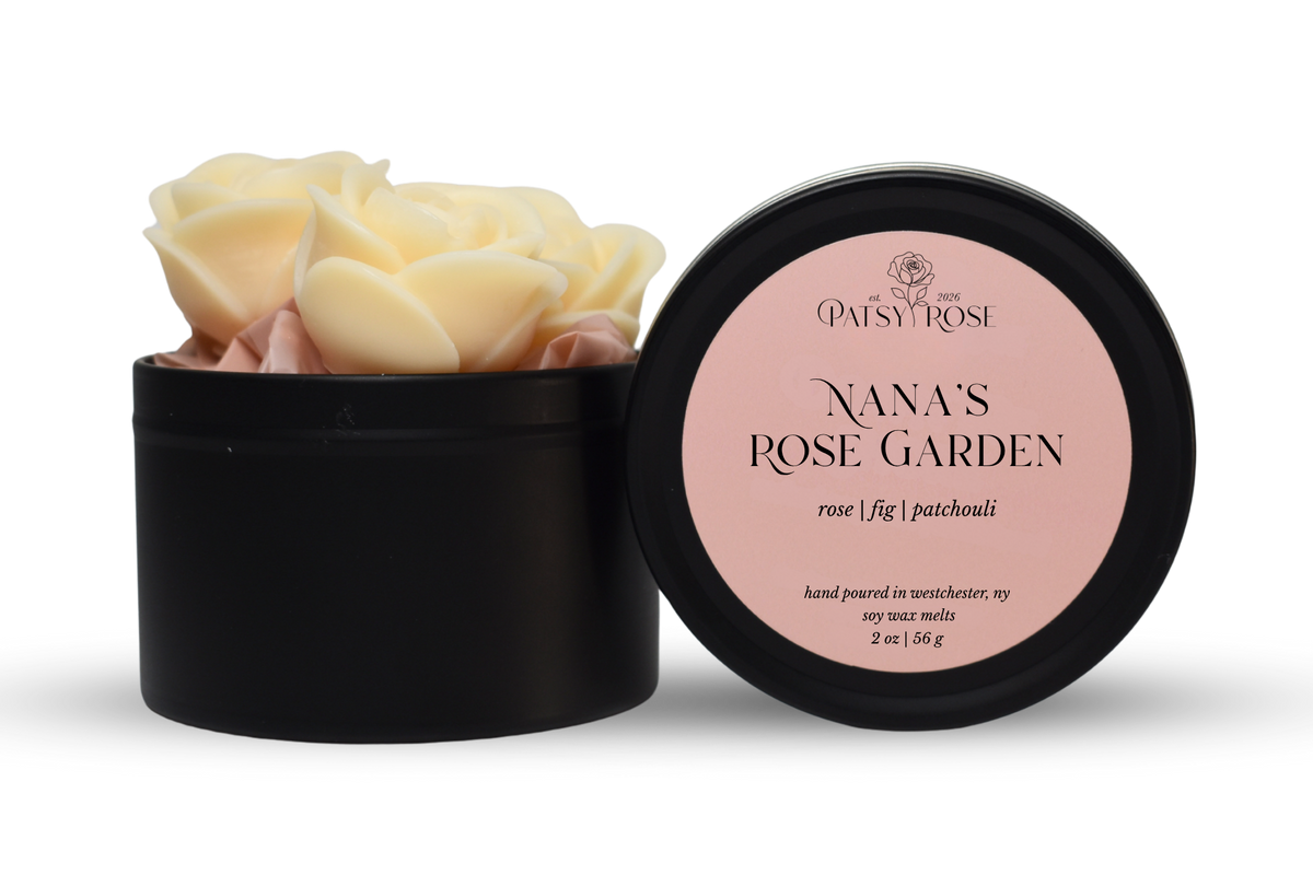 Hand-poured, rose shaped soy wax melts made by Patsy Rose with black tins and a peach label that says "Nana's Rose Garden" with scent notes of "rose, fig, patchouli".