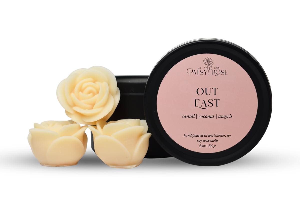 Hand-poured, rose shaped soy wax melts made by Patsy Rose with black tins and a peach label that says "Out East" with scent notes of "santal, coconut, amyris".