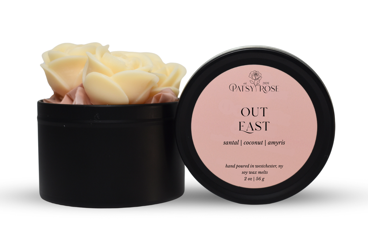Hand-poured, rose shaped soy wax melts made by Patsy Rose with black tins and a peach label that says "Out East" with scent notes of "santal, coconut, amyris".