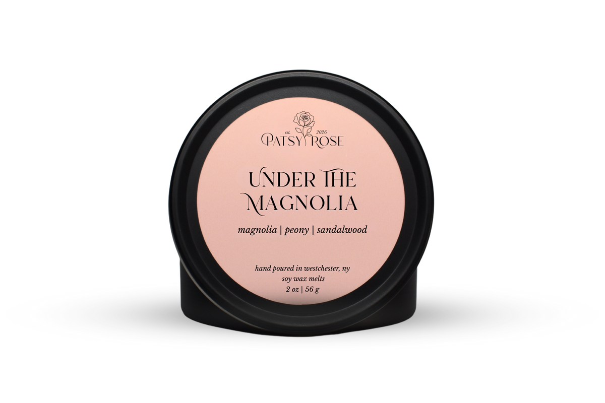 Hand-poured soy wax melts made by Patsy Rose with black tins and a peach label that says "Under the Magnolia" with scent notes of "magnolia, peony, sandalwood".