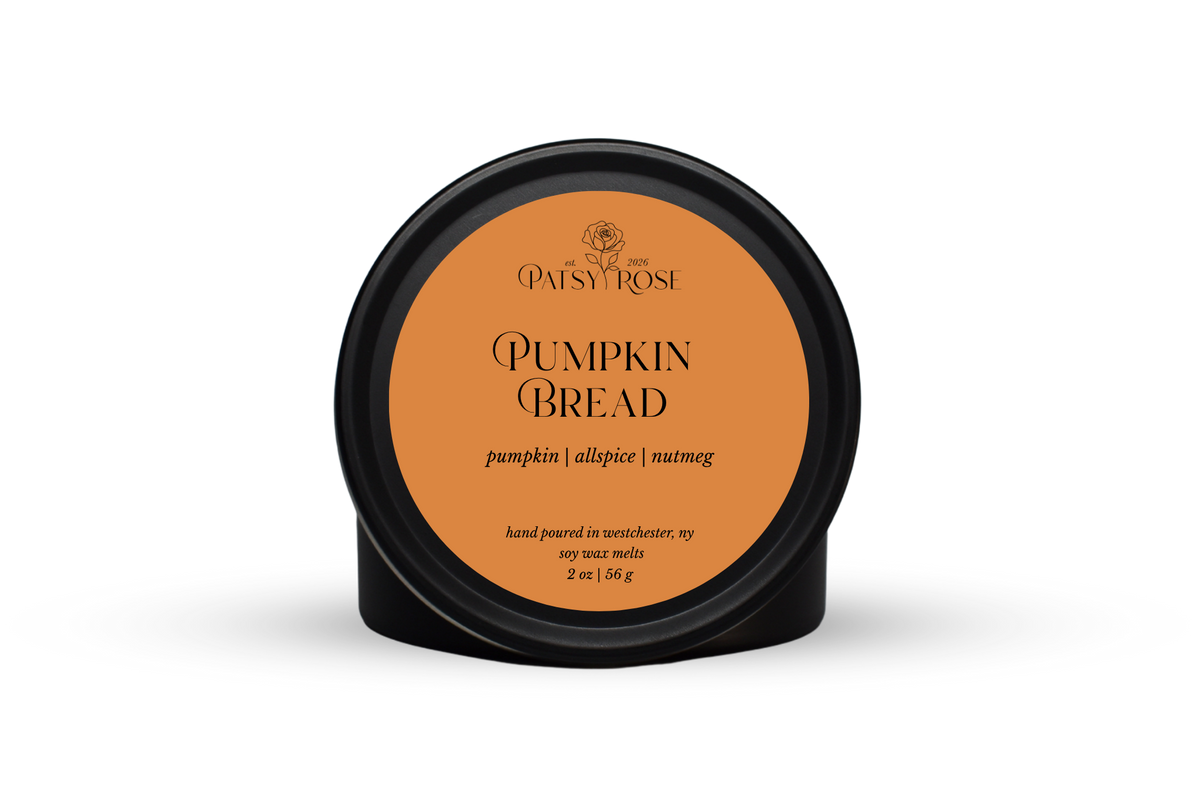 Hand-poured soy wax melts made by Patsy Rose with black tins and an orange label that says "Pumpkin Bread" with scent notes of "pumpkin, allspice, nutmeg".