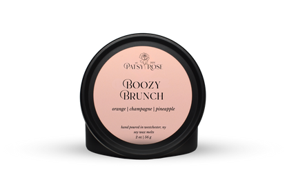 Hand-poured soy wax melts made by Patsy Rose with black tins and a peach label that says "Boozy Brunch" with scent notes of "orange, champagne, pineapple".